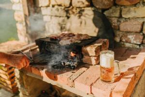 a glass of beer next to a brick oven at Kuća Mitića in Pirot