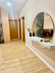 a living room with a mirror and a wooden floor at Your Home Fier 2 in Fier
