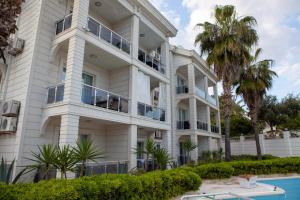 a large white building with a pool in front of it at Kemer Suit Residence in Kemer