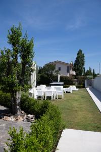 a group of white tables and benches in a yard at Villa Karina - Luxury Suite, Jacuzzi Pool & Garden Ostia Rome in Lido di Ostia