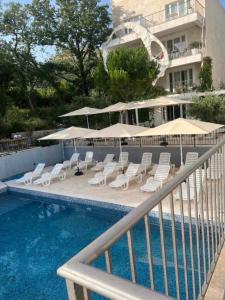 a swimming pool with lounge chairs and umbrellas next to a building at Mostoliva Sea View Studios in Pržno