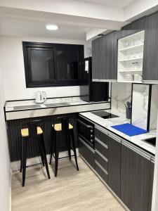 a kitchen with black cabinets and two bar stools at Montevideo Centro in Montevideo +4 photos