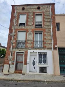 a brick building with a white door and windows at Love Room romantique avec Jacuzzi 2 places in Perpignan