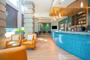 a restaurant with a swimming pool and orange chairs at Sandman Signature Surrey-Guildford Suites in Surrey