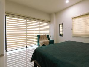 a bedroom with a bed and a chair and windows at Depa Amplio Vista al Mar Cerca del Malecón in Mazatlán +18 photos