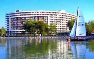 a sail boat in the water in front of a building at Enidor Wellness Apartman in Siófok