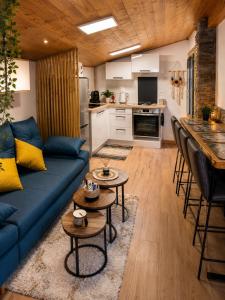 a living room with a blue couch and a kitchen at Maisonnette Cosy in La Llagonne