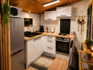 a kitchen with white cabinets and a stainless steel refrigerator at Maisonnette Cosy in La Llagonne