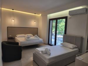 a bedroom with two beds and a chair and a window at Eden Rooms in Vlorë
