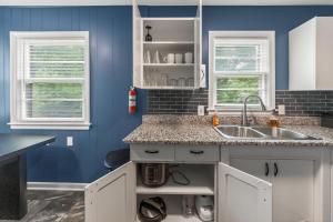 a blue kitchen with a sink and two windows at Chic Home with Huge Grassy Yard 7 mins to Arrowhead Stadium in Independence