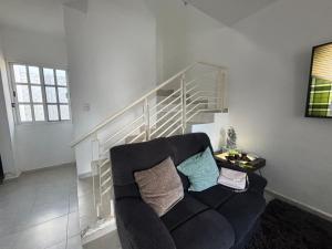 ein Wohnzimmer mit schwarzem Sofa und Treppe in der Unterkunft Casa Manu in Mérida