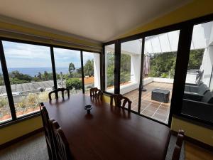 a dining room with a table and some windows at Machico View in Machico