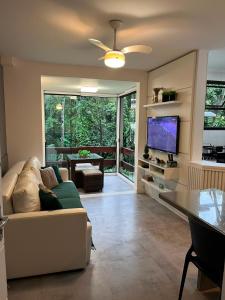 a living room with a couch and a flat screen tv at Apto Riviera Piscina Aquecida in Bertioga