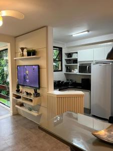 a kitchen with a refrigerator and a tv in it at Apto Riviera Piscina Aquecida in Bertioga