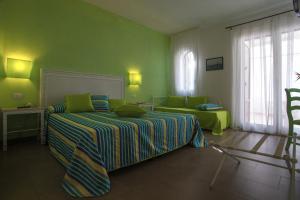 a green bedroom with a bed and a chair at Hotel O'scià in Lampedusa