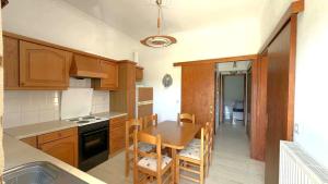 a kitchen with wooden cabinets and a table and chairs at Fokianos Gate in Peletá +3 photos