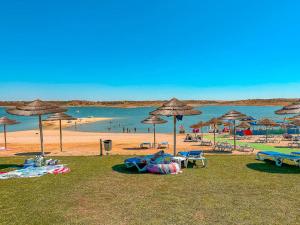 a beach with umbrellas and chairs and people in the water at Os Robalos in Moura