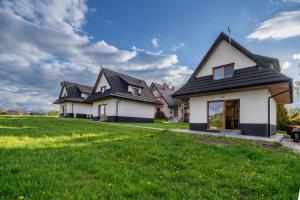 a house with a black roof on a green lawn at Biała Owca in Biały Dunajec