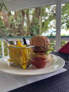 a plate with a hamburger and a basket of fries at Coral Quays Resort in Luganville