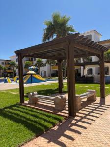 a wooden pavilion with a bench in a park at Marinamer 1 in Saïdia