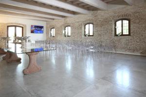 Habitación grande con copas de vino alineadas contra una pared de ladrillo. en Agriturismo Corte Capiluppia, en Curtatone