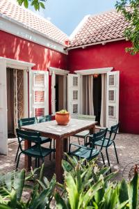 a table and chairs in front of a red house at Villa Tokara in Willemstad