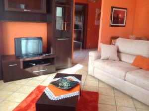 sala de estar con sofá y TV en Orange Holiday Home, en Torvaianica