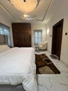 a bedroom with a large white bed and a chair at Velaris Luxury Apartment in Port Harcourt