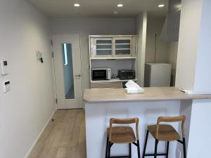 a kitchen with two bar stools and a counter top at ドリームホテル住吉 in Sumiyoshi