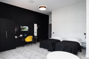two beds in a room with black walls and a desk at Hotel Absolwent in Gostyń