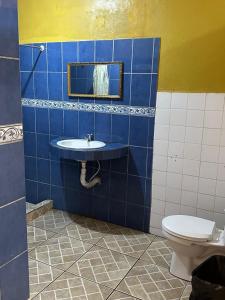 a blue tiled bathroom with a sink and a toilet at Cabinas Hilda in Canoas