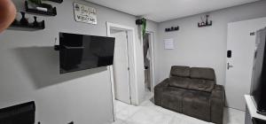 a living room with a chair and a flat screen tv at RG Kitnet05 in Curitiba