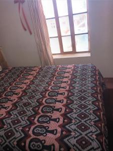 a bedroom with a bed with a patterned blanket on it at Hospedaje jatari in Estanciasuyo