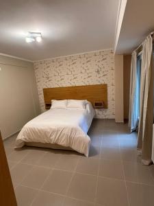 a bedroom with a white bed with a wooden headboard at Apart Hotel Ostrón in Rada Tilly +68 photos