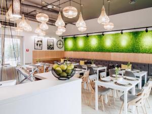 a restaurant with white tables and chairs and a green wall at Hotel Absolwent in Gostyń