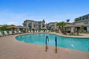 a swimming pool with chairs and buildings in the background at King Bed Remodeled and Walkable Adjacent Kierland Golf in Scottsdale