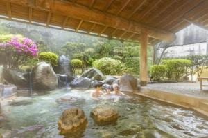 two children swimming in a hot tub in a garden at Ooedo Onsen Monogatari Premium Saiki Bekkan in Misasa