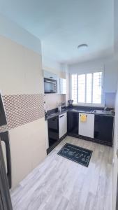 a kitchen with black and white cabinets and a kitchen rug at Perle de Tamaris Appartement Moderne, Bien Équipé, Piscine pour Enfants Parking in Casablanca