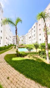 a pathway with palm trees in front of a building at Perle de Tamaris Appartement Moderne, Bien Équipé, Piscine pour Enfants Parking in Casablanca