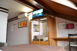 Un dormitorio con una cama y un televisor en la pared. en Hotel Apartamentos Don Juan I, en Alcalá de Henares