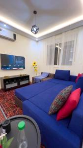 a living room with a blue couch and a tv at Perle de Tamaris Appartement Moderne, Bien Équipé, Piscine pour Enfants Parking in Casablanca