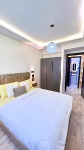 a bedroom with a large white bed in a room at Perle de Tamaris Appartement Moderne, Bien Équipé, Piscine pour Enfants Parking in Casablanca +15 photos