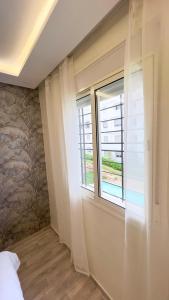 a bedroom with a window and a wall with a mural at Perle de Tamaris Appartement Moderne, Bien Équipé, Piscine pour Enfants Parking in Casablanca