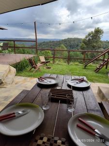 a wooden table with plates and glasses on top of it at Chacara Pôr do Sol Capivari in Campina Grande do Sul