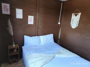 a bed with blue sheets and a wooden wall at Chacara Pôr do Sol Capivari in Campina Grande do Sul