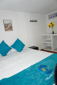 a bedroom with a white bed with blue pillows at MANDA PARaDISE HOUSE in Cartagena de Indias
