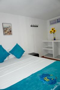 a bedroom with a white bed with blue pillows at MANDA PARaDISE HOUSE in Cartagena de Indias