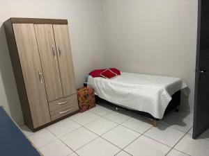 a small bedroom with a bed and a wooden cabinet at Pousada de Sá in Uberlândia