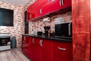 a kitchen with red cabinets and a microwave at Kumbaya Apartments in Achimota