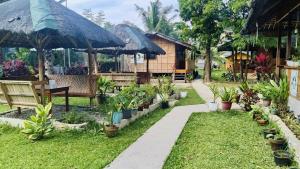 a garden with a bench and a house with plants at Hidden Paraiso Resort in Puerto Galera